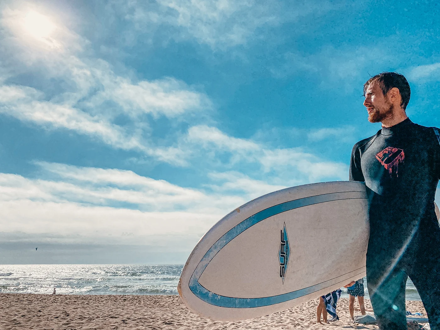Roman holding a surfboard by the ocean
